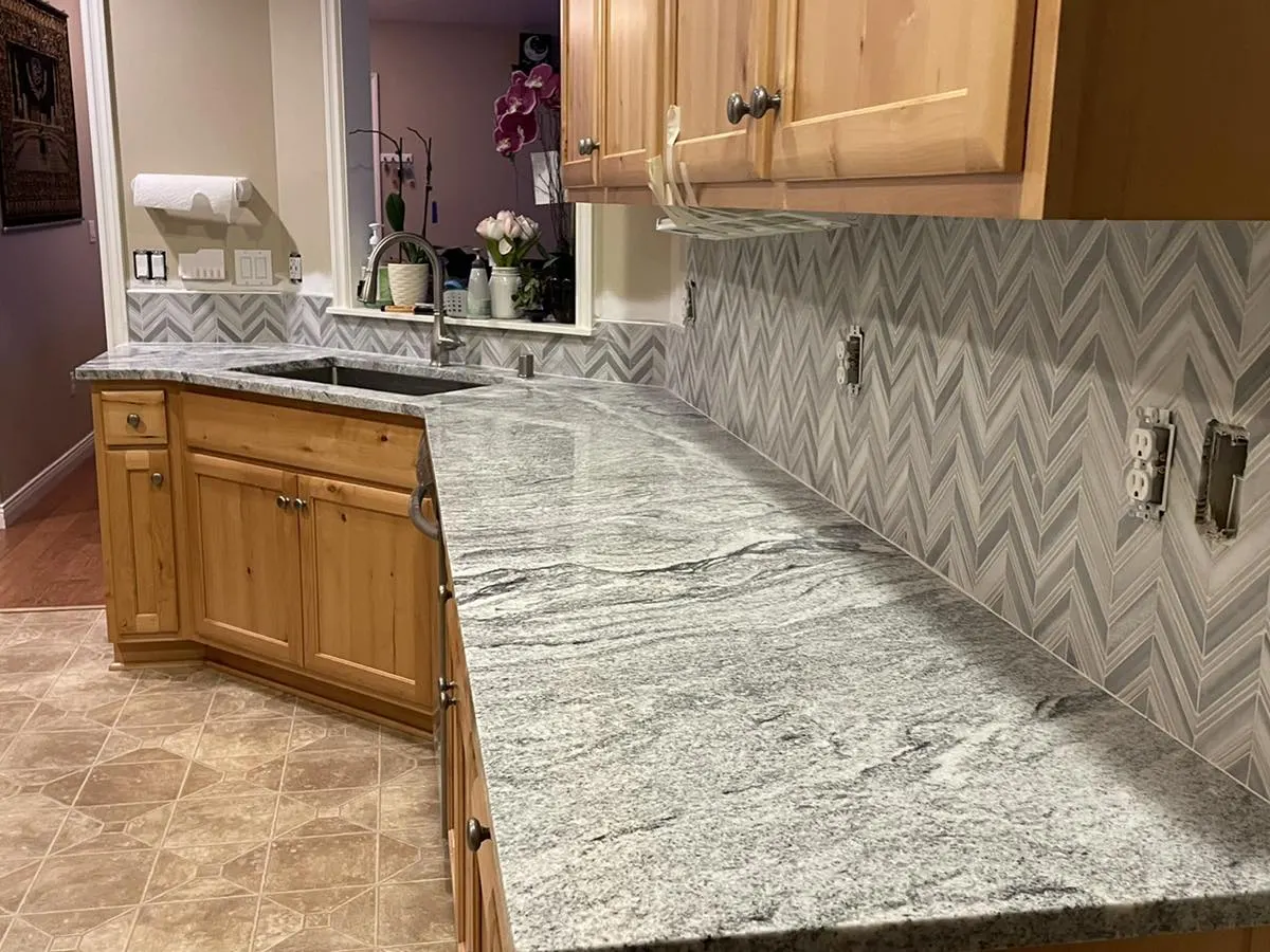 Kitchen with a chevron tile backsplash and granite countertop