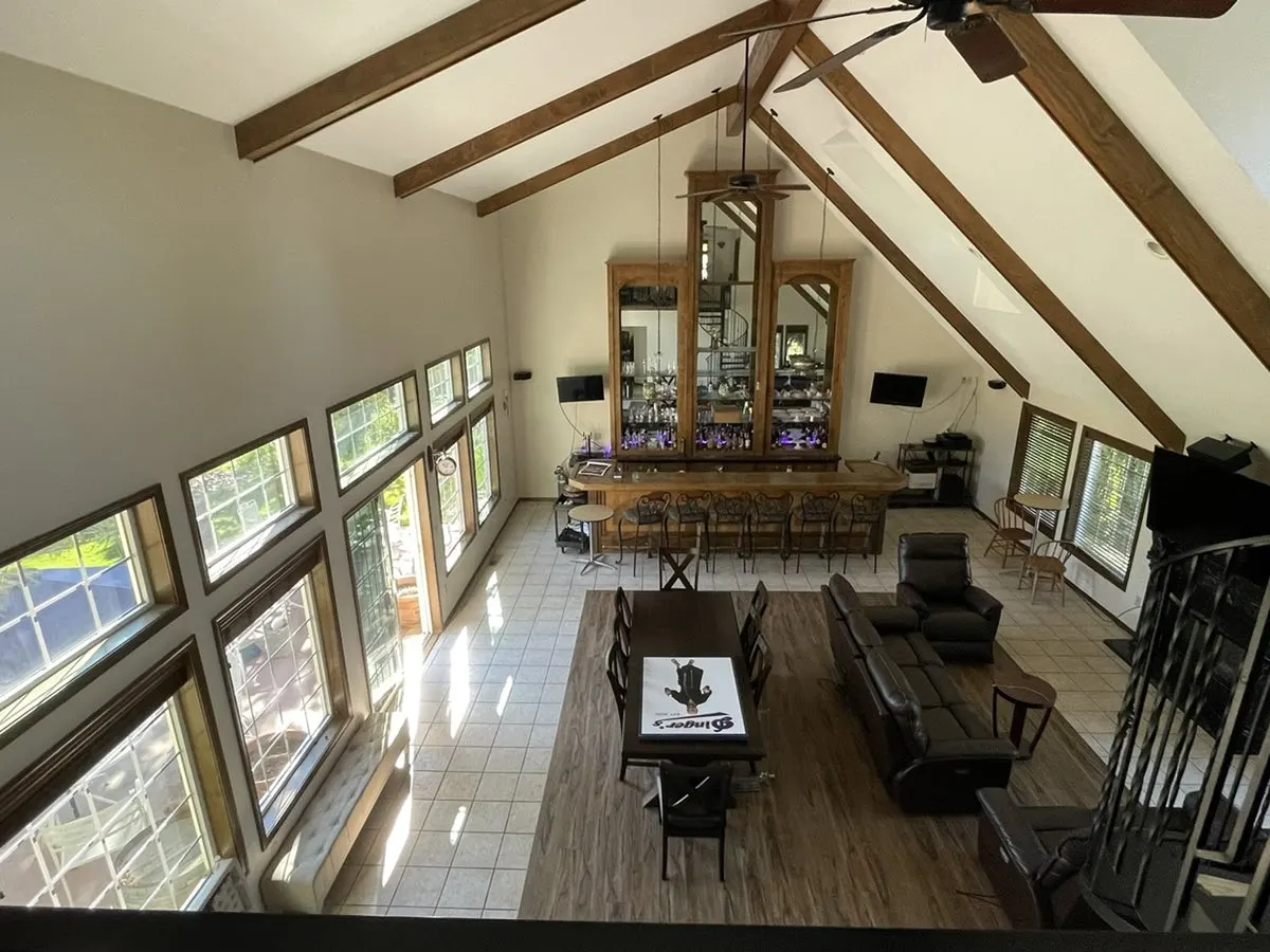 Large great room with vaulted ceiling, wood beams and tall windows